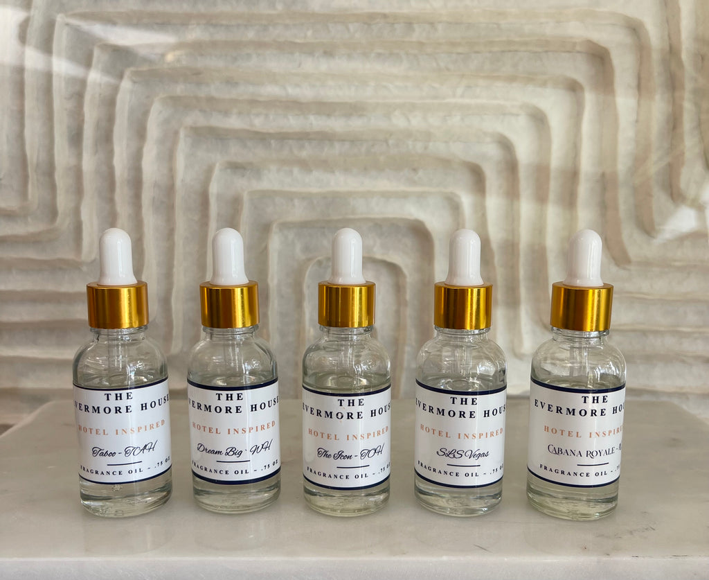 Five glass dropper bottles with gold caps on a textured stone surface.